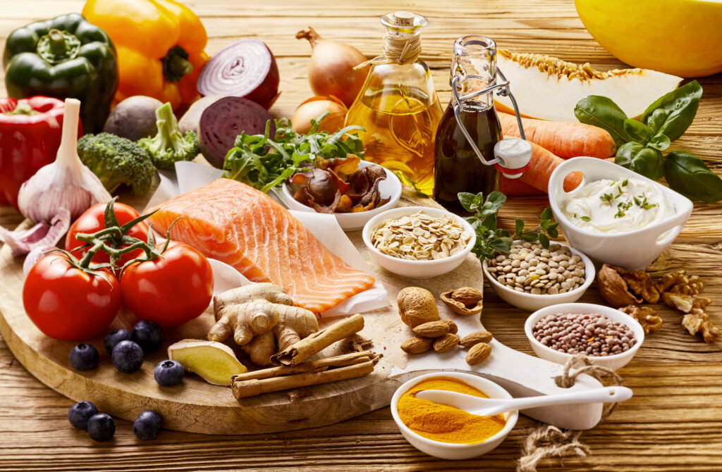 Omega-3 rich foods: salmon, spices, lentils, herbs, blueberries, broccoli, garlic, tomato, nuts, soy sauce, carrots and olive oil on a rustic table